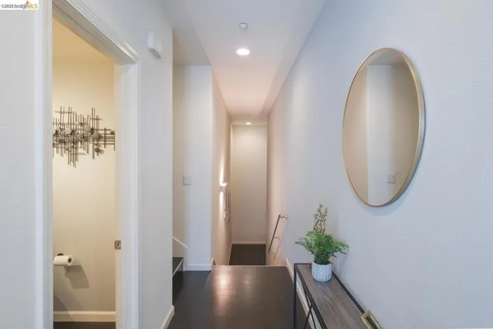 Hallway featuring dark wood-finish flooring, recessed lighting, and a white trim entry to an additional space
