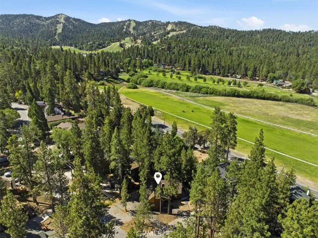 Aerial neighborhood view with the property set among pine trees near golf course and ski slope