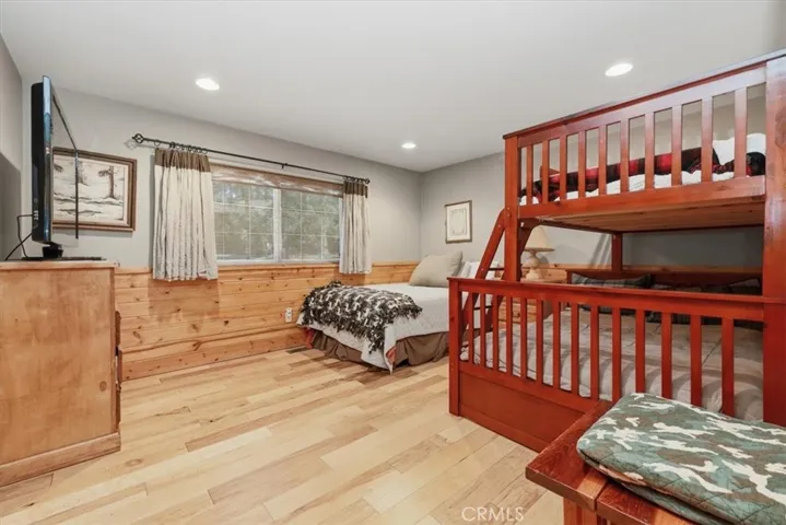 Bedroom with wood flooring, bunk beds, additional sleeping area, and large window.