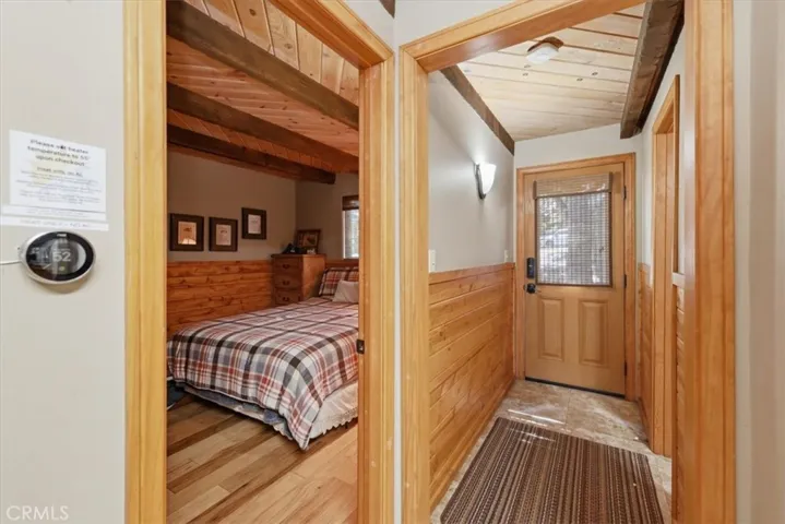 Entry hallway with wood wainscoting, front door, and nearby bedroom access.