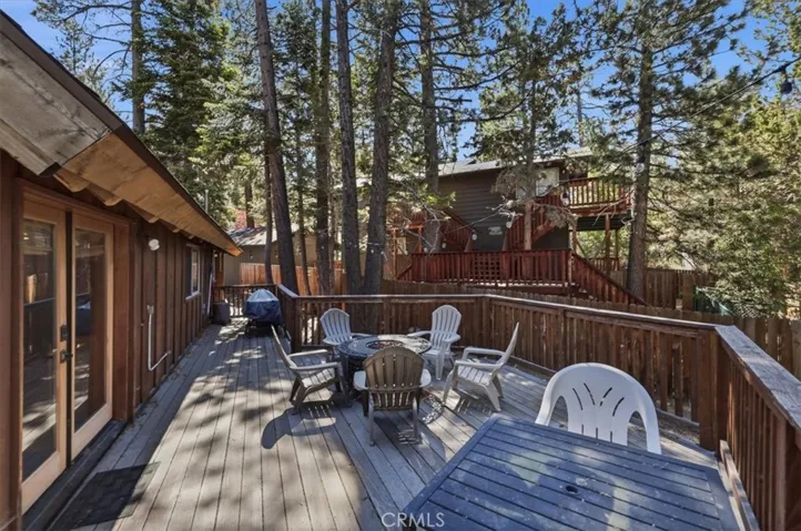 Spacious deck with multiple seating areas and views of the surrounding trees.