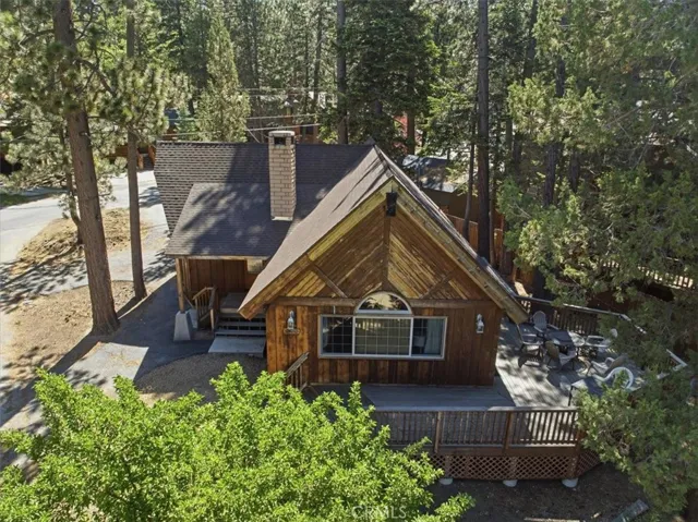 Aerial front view of the cabin with deck space and wooded setting.