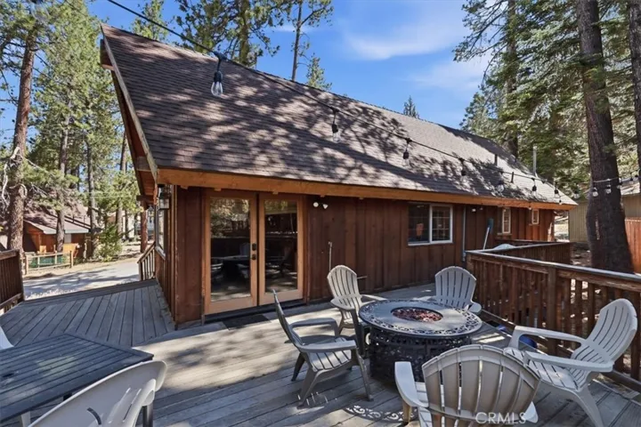 Deck area with outdoor seating, French doors, and wooded surroundings.