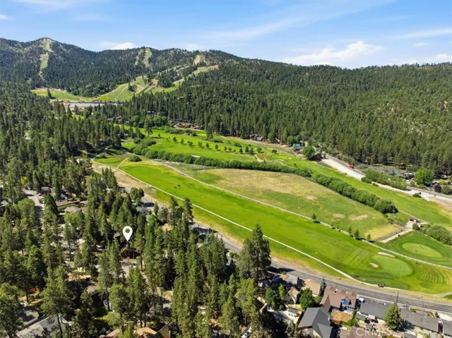 Aerial view of the property area with surrounding trees, neighborhood streets, and mountain views.