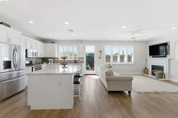 Kitchen with open floor plan, stainless steel appliances, a center island, dark wood-type flooring, and a kitchen breakfast bar