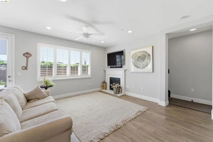 Living area with ceiling fan, light wood-type flooring, a fireplace, and recessed lighting