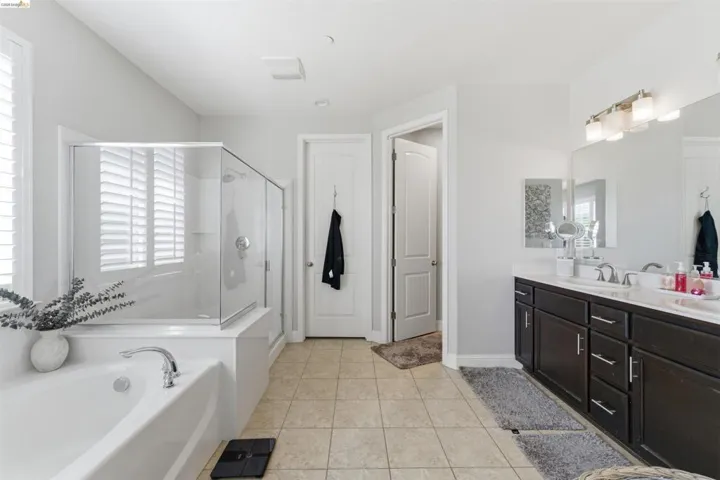 Full bathroom with vanity, a shower stall, light tile patterned flooring, and a garden tub