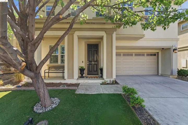 Property entrance with stucco siding, concrete driveway, a yard, and a garage