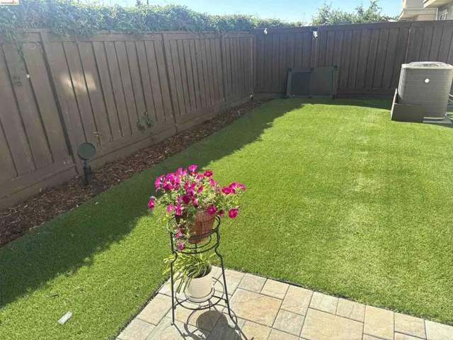 Private backyard featuring artificial turf, a wood fence, and stone paver patio