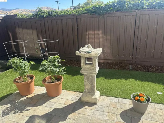 Backyard patio featuring square-cut pavers, artificial turf, and a perimeter privacy fence