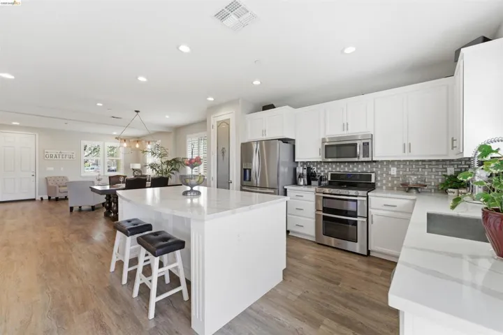 Kitchen with stainless steel appliances, a breakfast bar, a kitchen island, and white cabinetry