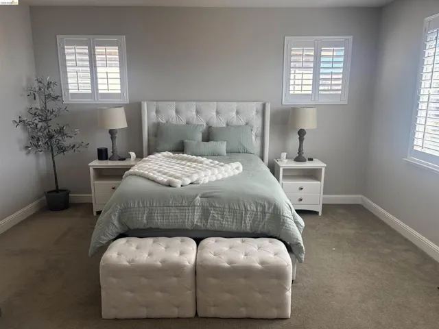 Spacious bedroom featuring neutral carpet flooring, light gray wall paint, and white baseboards