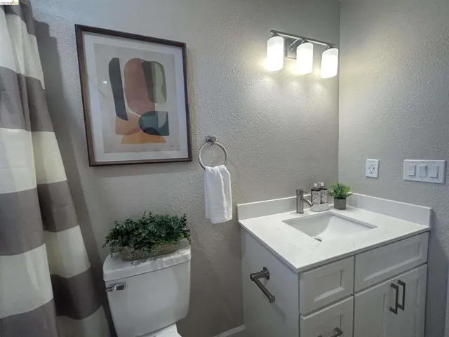 Modern bathroom vanity with a white countertop and integrated sink, brushed nickel faucet, and a three-light vanity fixture