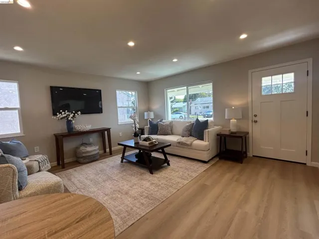 Bright living area featuring wood-finish flooring, recessed lighting, multiple windows, and a panel door with upper glass inserts