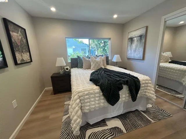 Bright sleeping area featuring wood-finish flooring, recessed lighting, and a window with exterior views