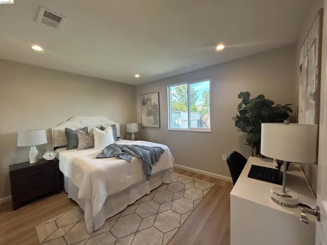 Room featuring wood-finish flooring, recessed lighting, and a window providing natural light