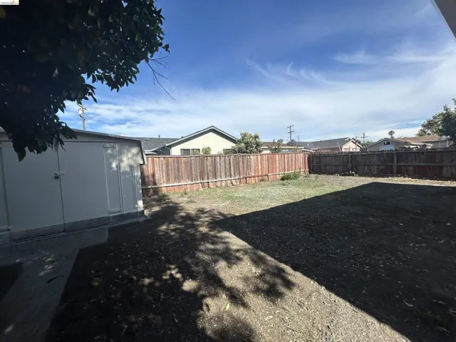 Expansive backyard featuring a large open area, perimeter wood fencing, and an integrated storage shed
