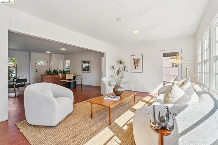 Bright living area featuring white paneling, multiple windows, a wide entry to an additional space, and recessed lighting