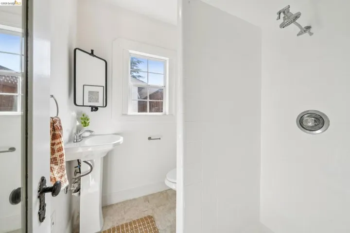 Bathroom featuring a white pedestal sink, tiled flooring, and a shower with a recessed light and showerhead