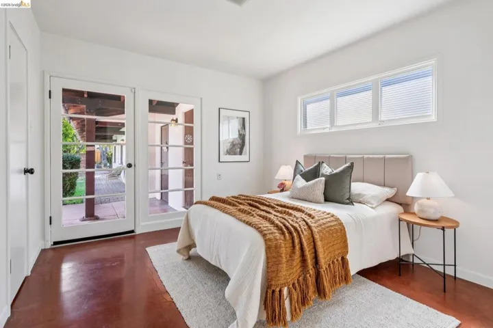 Bedroom featuring rich red-toned flooring and white walls