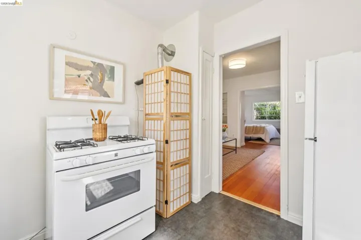 White oven range with visible stovetop burners, contrasting with dark flooring