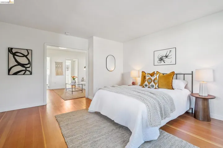 Hardwood-style flooring throughout, white walls, and an open doorway leading to an additional living space