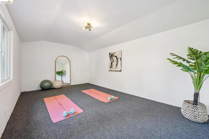 Spacious room featuring vaulted ceilings, a window with white trim, and dark gray carpeting