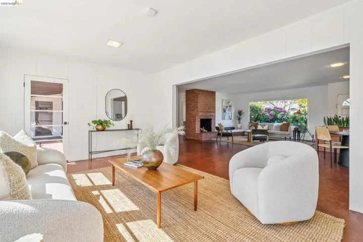 Expansive open-concept living area featuring a brick fireplace, large picture window, and wood-finish flooring