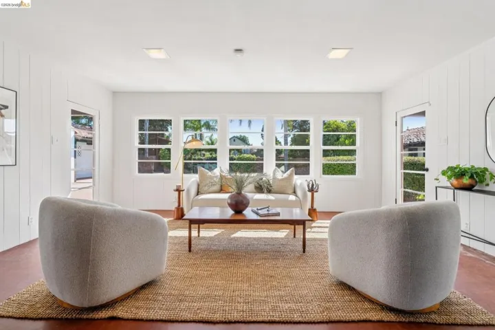 Living area featuring rich wood flooring, white vertical plank wall paneling, and a large multi-pane window array
