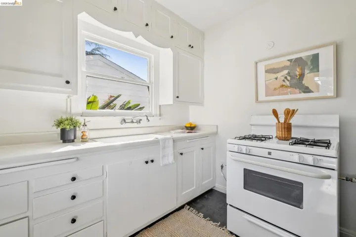 Kitchen featuring white cabinetry with black hardware, white countertops, and a white gas range