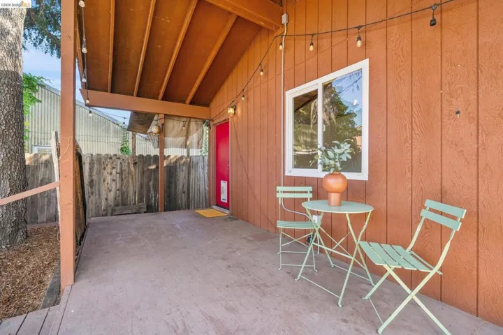 Covered patio featuring a wood-finish ceiling, board and batten siding, and a red entry door