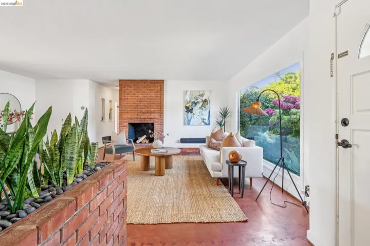Living area featuring a brick fireplace, a large picture window, and light-toned flooring