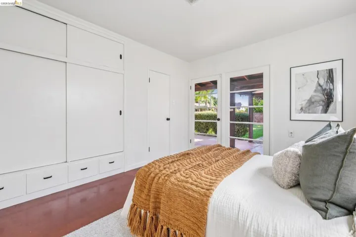 Room featuring built-in cabinetry with sliding and drawer storage, a solid door, and a pair of glass-paned French doors opening to an exterior patio and lawn