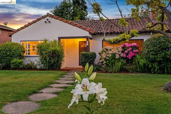 Stucco exterior with a terracotta tile roof, featuring a covered entry porch and arched wooden door