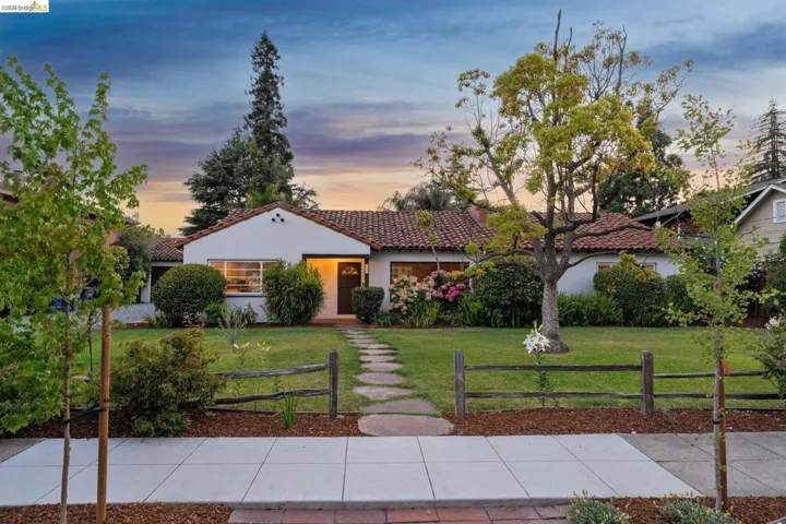 Stucco exterior with a terra cotta tile roof, framed by a stone path and manicured lawn