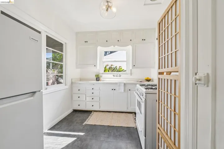 White cabinetry with black hardware, white countertop surfaces, and a built-in gas range