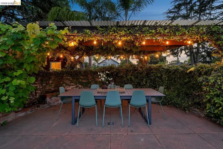 Patio area featuring a pergola with string lights and extensive vine coverage