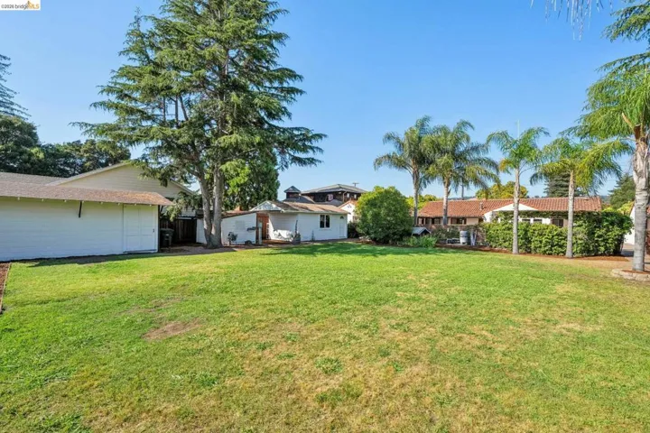 Expansive lawn area with mature trees and perimeter landscaping