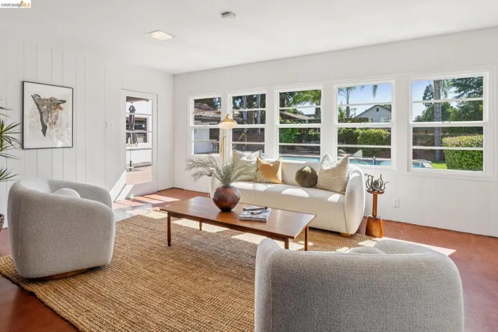 Bright interior room featuring a wall of multiple windows, white paneling, and terra cotta-toned flooring