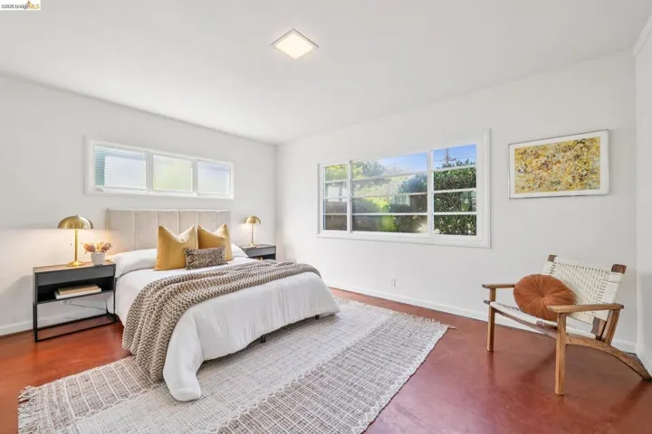 Spacious room featuring wood-finish flooring, white walls, and multiple windows including transoms