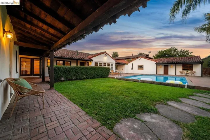 Expansive backyard featuring a rectangular swimming pool, manicured lawn, and brick patio