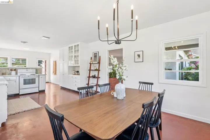 Open-concept dining area featuring a modern black chandelier and wood-finish flooring