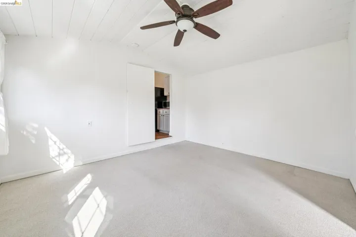 Carpeted room with a white plank ceiling and a ceiling fan