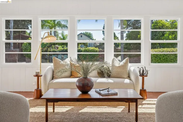 Bright living area featuring a wall of multiple pane windows, white paneling, and wood-finish flooring