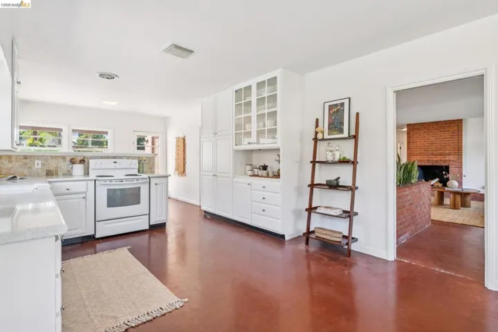 Bright kitchen featuring white cabinetry, a white range, light countertops, and a stone-tile backsplash