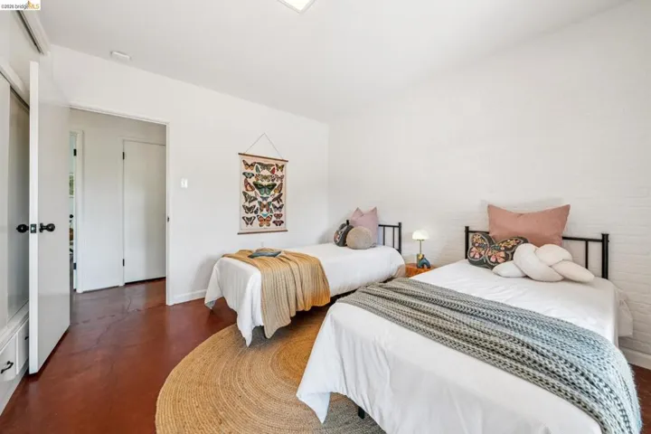 Bedroom featuring white walls and rich brown flooring