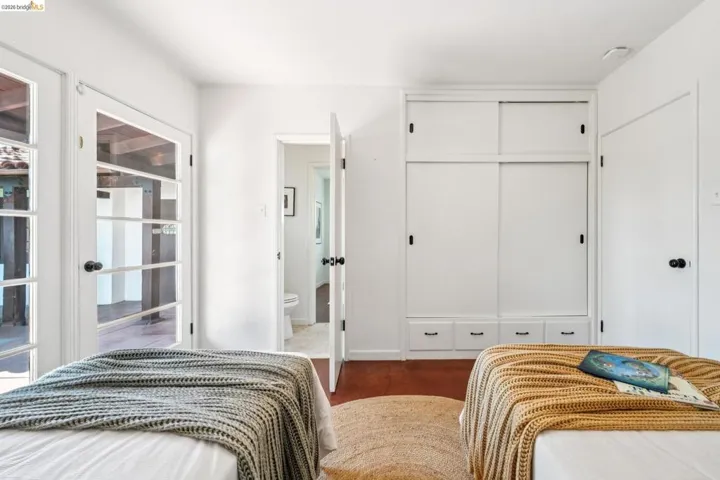 Bedroom featuring wood-finish flooring, two French doors with dark hardware, and a built-in wardrobe with sliding doors and integrated drawers