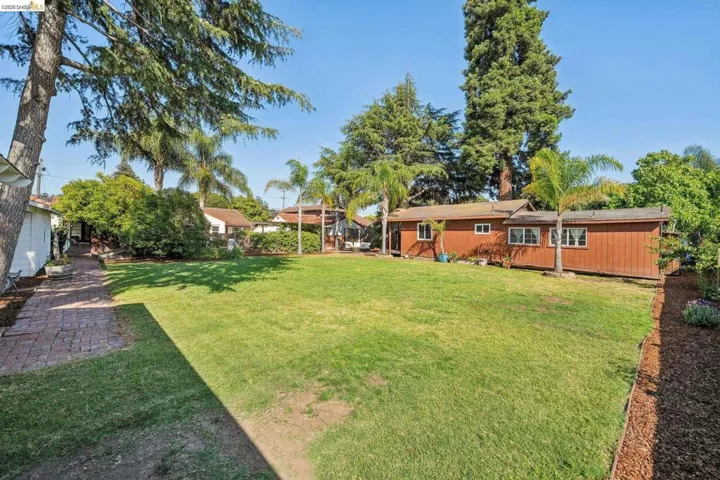 Expansive lawn area featuring mature trees and a brick-paved pathway