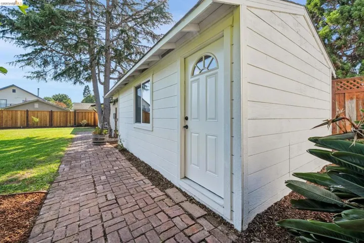 Detached utility building featuring horizontal siding, a paneled door with an arched window, and a single window