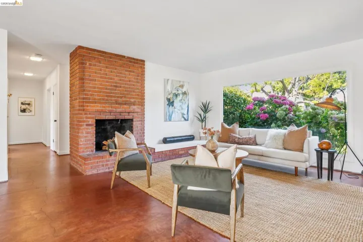 Spacious living area featuring a prominent brick fireplace, large picture window, and rich wood-finish flooring